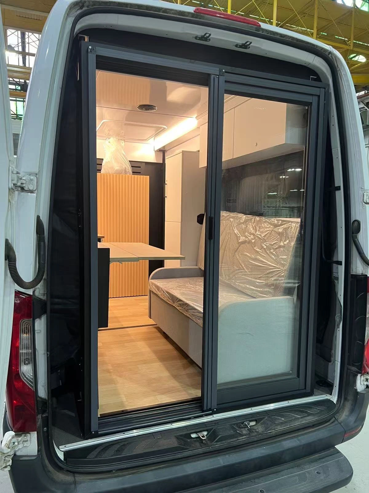 Actual camper module installed in a van, viewed through the rear doors